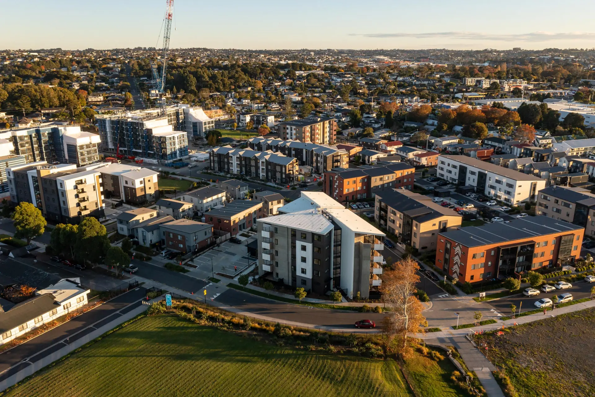 Aerial view of a completed medium-density housing development, with apartment blocks and terraced homes among established streets.
